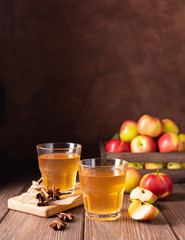 Apple drink or cider with thyme cinnamon spices in transparent glasses on a dark wooden background....
