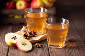 Apple drink or cider with thyme cinnamon spices in transparent glasses on a dark wooden background. Home Sangria. Autumn concept. Front view. Copy space.