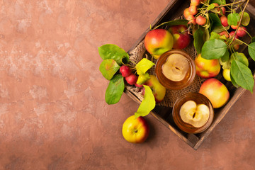 Apple drink or cider in glass cups on a dark wooden spread decorated with slices of apples. Autumn concept. View from above. Horizontal frame. Copy space.