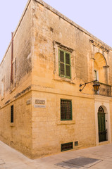 Fototapeta na wymiar Mdina, Malta. Ancient building at the corner of Holy Cross Street and Aragona Alley