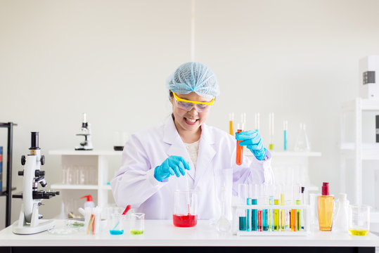 Happy scientist woman study and putting medical chemicals sample in test tube at laboratory
