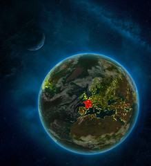 France from space on Earth at night surrounded by space with Moon and Milky Way. Detailed planet with city lights and clouds.