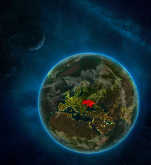 Ukraine from space on Earth at night surrounded by space with Moon and Milky Way. Detailed planet with city lights and clouds.
