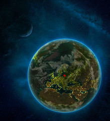 Lithuania from space on Earth at night surrounded by space with Moon and Milky Way. Detailed planet with city lights and clouds.