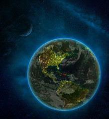 Haiti from space on Earth at night surrounded by space with Moon and Milky Way. Detailed planet with city lights and clouds.