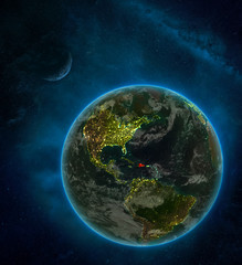 Dominican Republic from space on Earth at night surrounded by space with Moon and Milky Way. Detailed planet with city lights and clouds.
