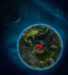 Venezuela from space on Earth at night surrounded by space with Moon and Milky Way. Detailed planet with city lights and clouds.