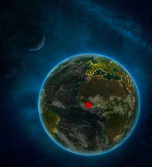 Ivory Coast from space on Earth at night surrounded by space with Moon and Milky Way. Detailed planet with city lights and clouds.