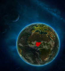 Nigeria from space on Earth at night surrounded by space with Moon and Milky Way. Detailed planet with city lights and clouds.