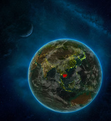 Cambodia from space on Earth at night surrounded by space with Moon and Milky Way. Detailed planet with city lights and clouds.