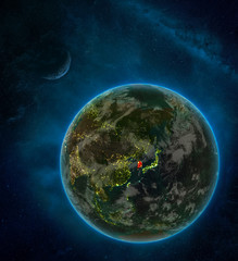 South Korea from space on Earth at night surrounded by space with Moon and Milky Way. Detailed planet with city lights and clouds.