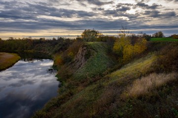 Calm narrow river with steep banks in countryside