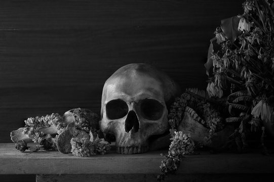 Skull with bone and withered  flowers in the vase whis has old wreath on the plank