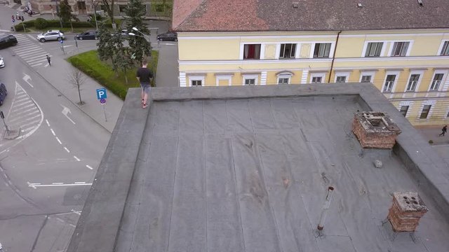 Overhead Aerial Drone Shot of a Young Adult Male Thrill Seeker Getting Ready to Jump of a Roof Top.