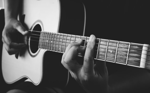 guitarist's hand on strings on dark background