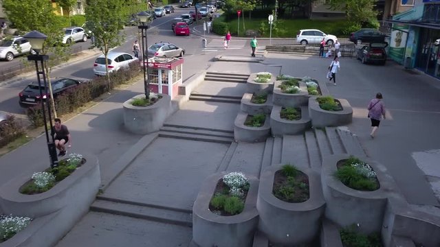 Aerial Drone Shot of a Young Adult Male Thrill Seeker Leaping Over a Very Large Flower Bed Structure.