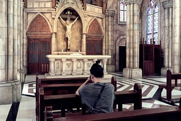 Rear view of young man praying in a church.
casual Man praying in church (vintage filter tone)