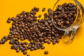 Spilled coffee beans on a bright yellow background