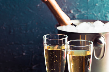 Champagne bottle in bucket with ice and glasses of champagne