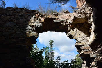 A window/arch at the entrance of a romanesque church in a spanish village. A beautiful landscape may be seen through it.
