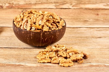 Peeled walnuts in the brown bowl on wooden table with copy space, close-up