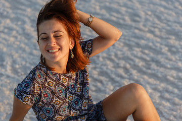 Fototapeta na wymiar happy smiling girl enjoying the sunset sun and shakes her head, sits on the salt