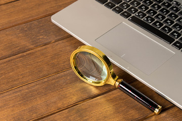 Magnifying glass on the laptop keyboard. The concept of information search on the Internet