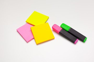 Sticky notes with markers, colored pens, paper clips laying on a table