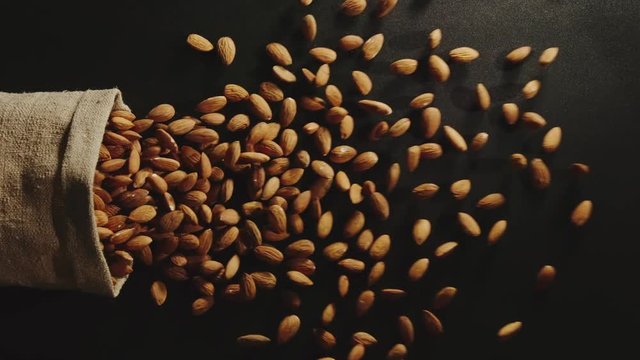 TOP VIEW: Bag falls and peeled almonds are poured out of it - Slow Motion