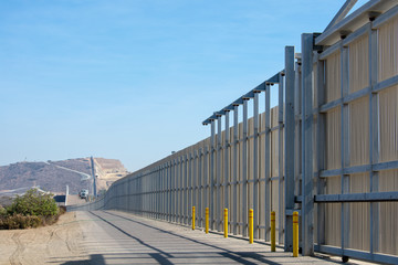 Fototapeta na wymiar The border wall on the United States - Mexico international border near San Diego in California under blue sky