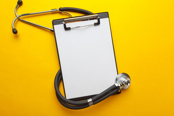 Flat lay design of stethoscope and blank clipboard pad with for medical concept.