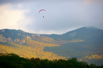 Paraglider over mountains at autumn day