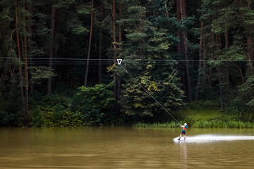 Fototapeta na wymiar Wakeboard. Man wakeboarding on lake in the forest. Active lifestyle. Extreme water sport.