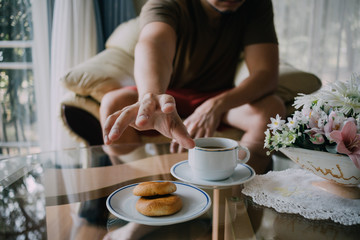 Man reaching to grab cookies and coffee.