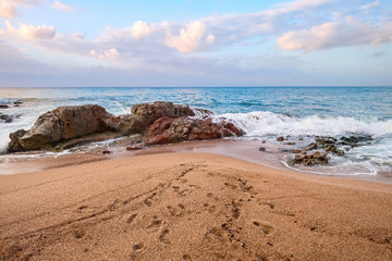Beautiful sunrise by the sea with human footprint on sand