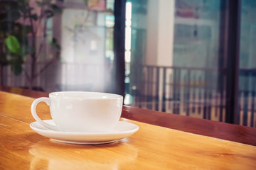 Cup of coffee on wood table in cafe  in vintage color mood ,Morning light