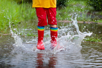 Kid with umbrella playing in summer rain.