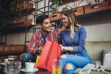Young couple enjoying in modern cafe after shopping.