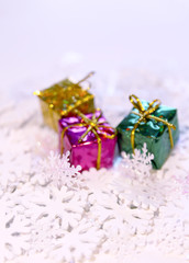 Fototapeta na wymiar Group of small bright colorful gift boxes on white artificial snowflakes background