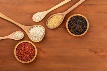 An assortment of rice types, shot from above on a rustic wooden background with copy space. Red, black, yellow, Asian, Spanish and Italian rices with a place for text