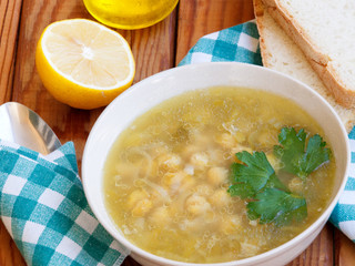 Chickpea soup on wooden table with bread and lemon on background