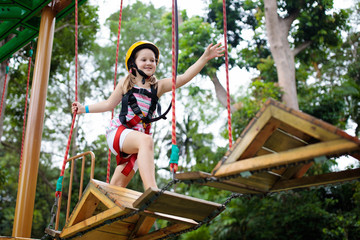Child in adventure park. Kids climbing rope trail.