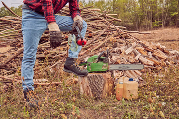 Naklejka premium Lumberjack with chainsaw and pile of cut woods.