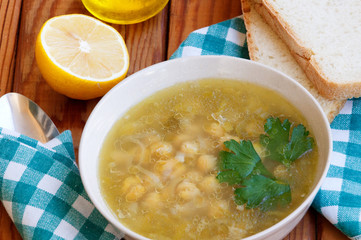 Chickpea soup on wooden table with bread and lemon on background