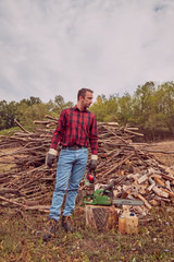 Fototapeta premium Lumberjack with chainsaw and pile of cut woods.