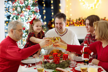 Family with kids having Christmas dinner at tree