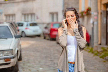 Cute young woman using cellphone in urban surroundings.