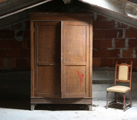dusty attic of the house with a wooden wardrobe and an old ramsh