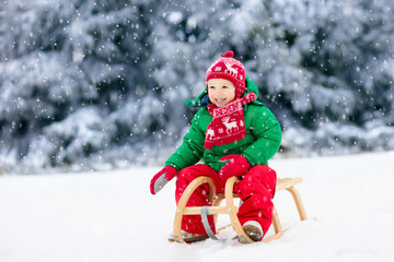 Boy on sleigh ride. Child sledding. Kid with sledge