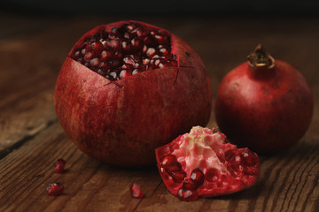 Beautiful composition with juicy pomegranates, on old wooden table